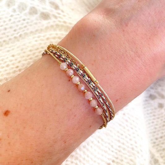 Bracelet composé de 4 liens en cordons dorés et chaîne dorée. Sur l'un d'eux sont montées 7 perles rondes de pierre naturelles de pierre de lune pêche.