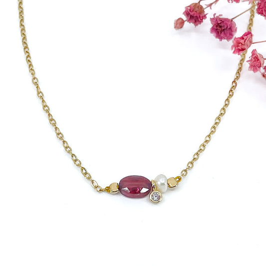 Collier en pierre fine naturelle Grenat orné d'une perle de culture et d'un petit pendentif cristal éclatant. Monté sur chaîne dorée en acier inoxydable.