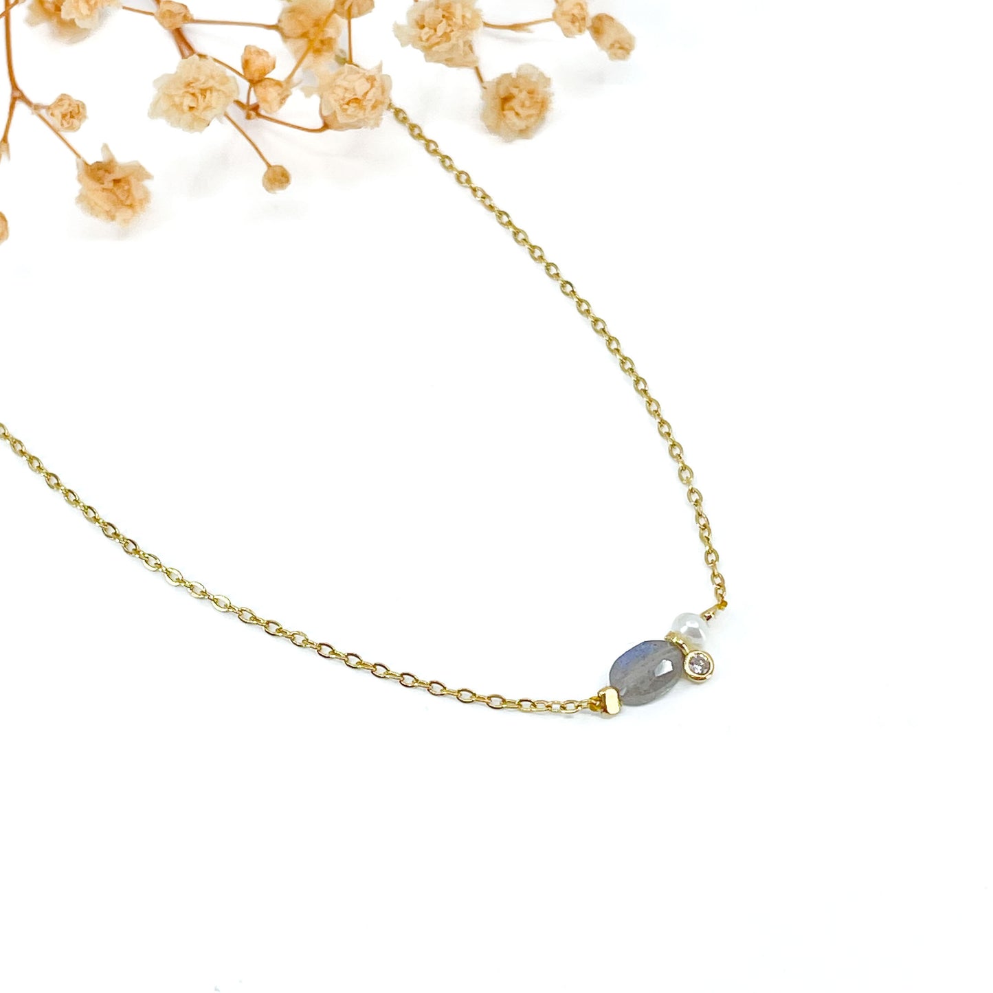 Collier en pierre fine naturelle Labradorite orné d'une perle de culture et d'un petit pendentif cristal éclatant. Monté sur chaîne dorée en acier inoxydable.