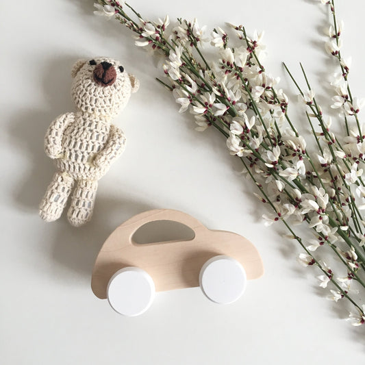 Voiture en bois naturel aux petites roues blanches. Jouet à pousser.