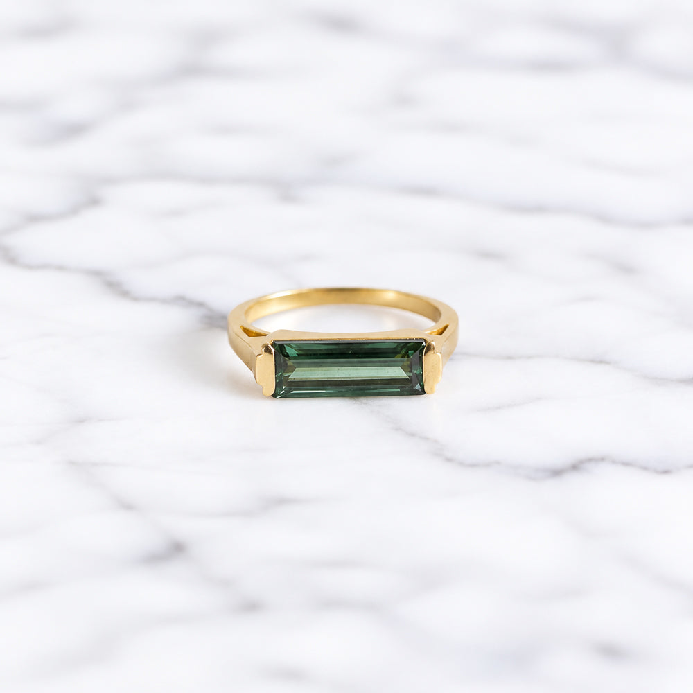 Bague avec pierre de tourmaline verte rectangulaire montée sur un anneau en laiton plaqué or aspect mat.