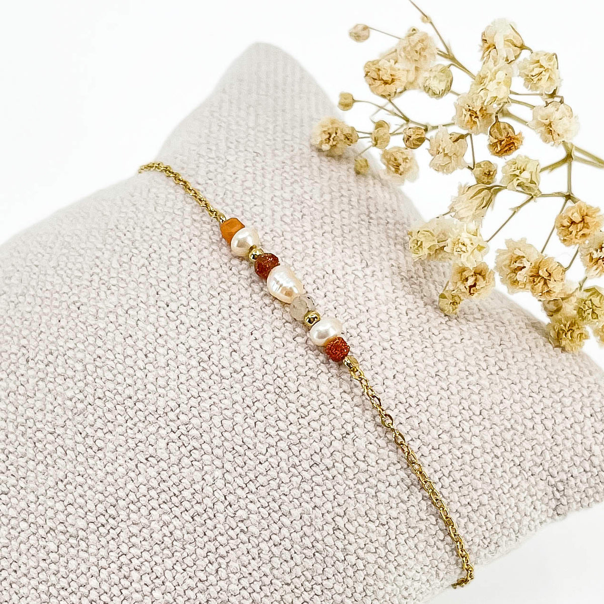 Bracelet monté avec une alternance de perles de culture et de pierres de lune naturelles et perle de verre pailletée de teinte terracotta sur une chaîne dorée.