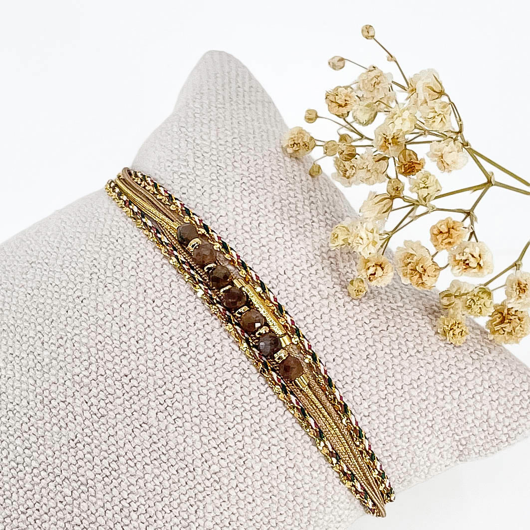Bracelet composé de 4 liens en cordons doré et taupe et chaîne dorée. Sur l'un d'eux sont montées 7 perles rondes de pierre naturelles de Quartz Fumé brun taupe
