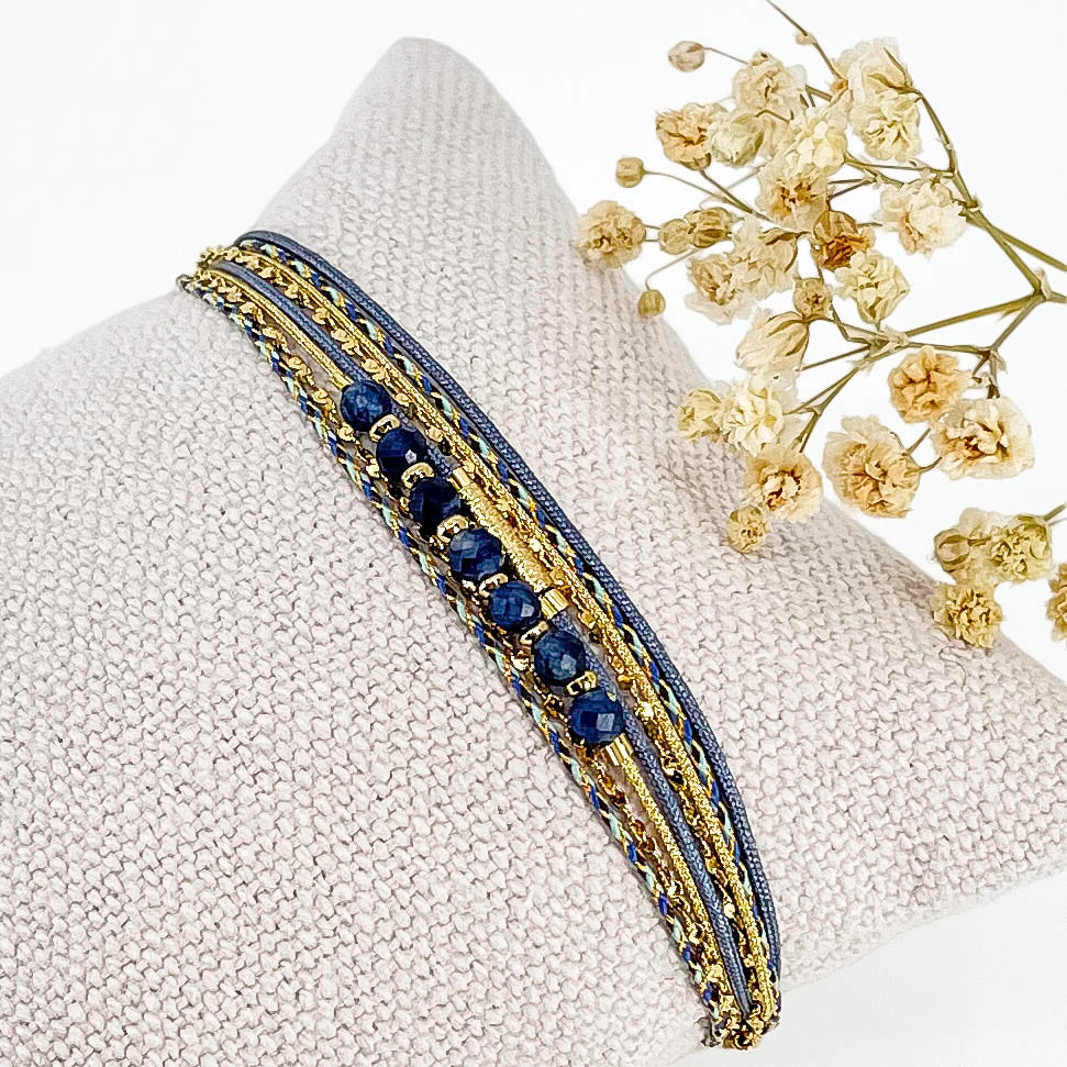 Bracelet composé de 4 liens en cordons doré et bleu et chaîne dorée. Sur l'un d'eux sont montées 7 perles rondes de pierre naturelles d'Agate bleue