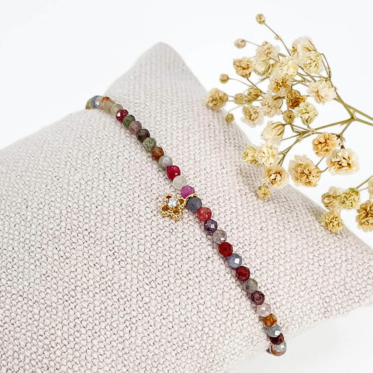 Bracelet pierres naturelles perles de tourmaline multicolores. En son centre un petit pendentif trèfle doré serti d'un cristal.