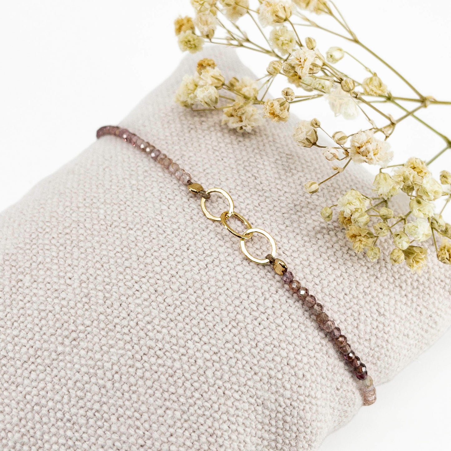 Bracelet réglable en pierres fines naturelles spinelle déclinaison de teinte rose et brune. Trois anneaux en plaqué or entremêlés