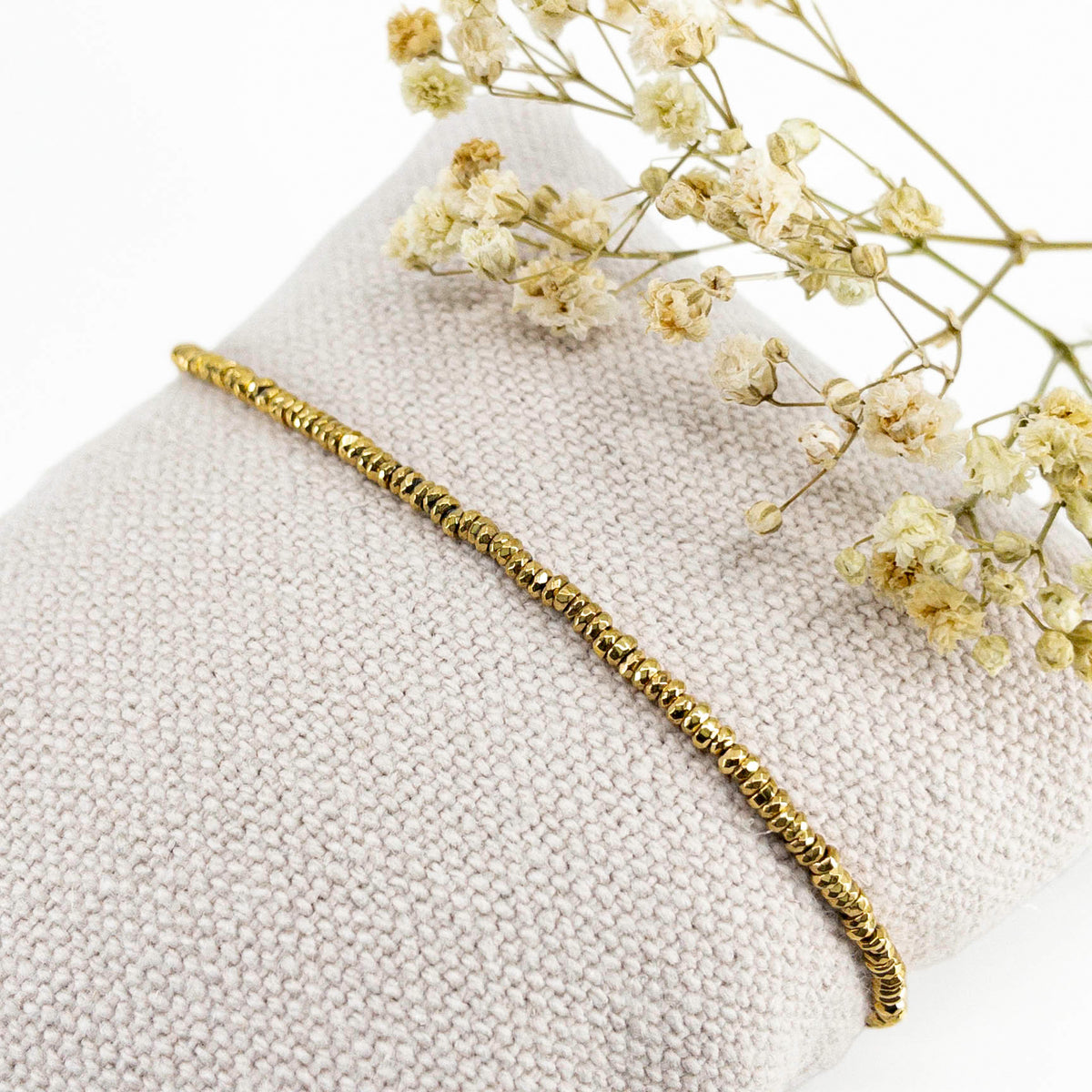 Bracelet en perles de pierre naturelle d'hématite dorée montées sur un cordon ajustable à la taille de votre poignet.