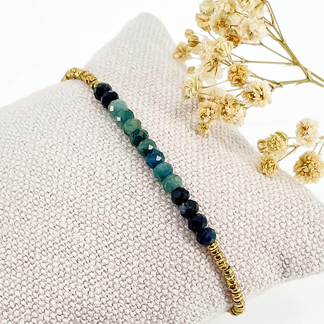 Bracelet en perles de pierres fines naturelles de Tourmaline bleu-vert intense. Elle sont encadrées de perles d'Hématites dorées.