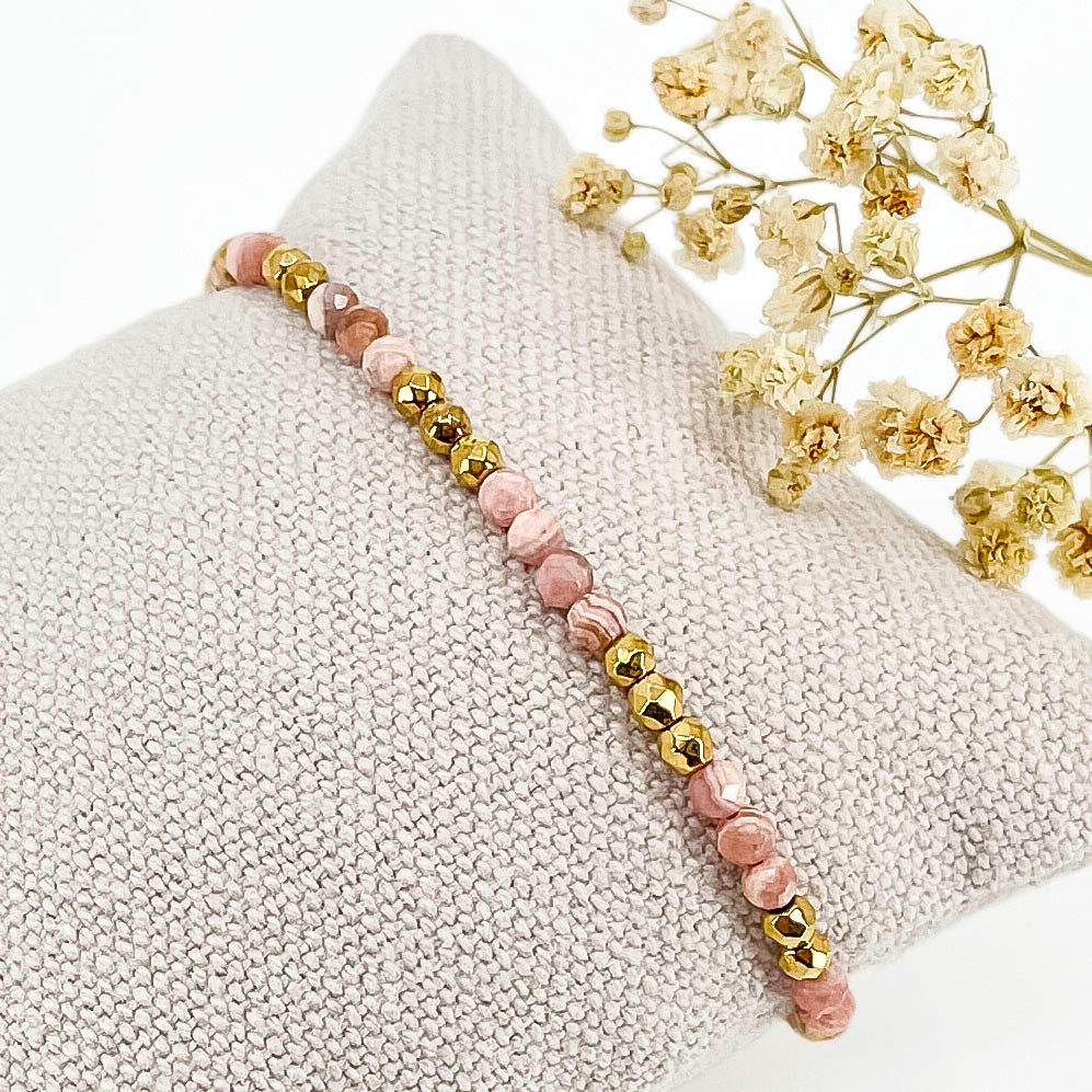 Rivière en pierres fines naturelles en perles facettées rose de rhodochrosite alternant avec des perles d'hématite dorée.