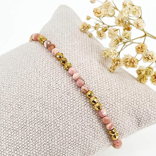 Rivière en pierres fines naturelles en perles facettées rose de rhodochrosite alternant avec des perles d'hématite dorée.