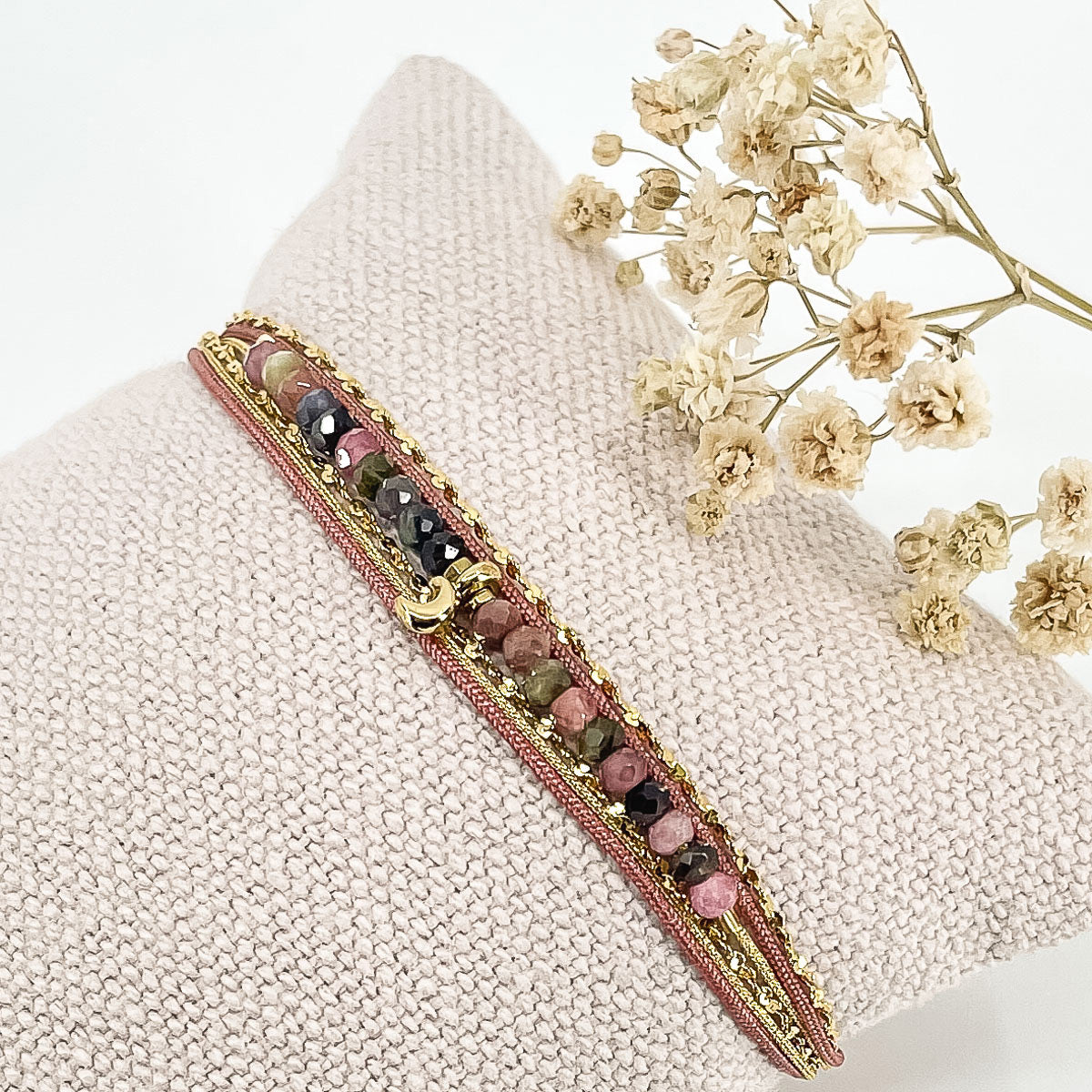 Bracelet composés de plusieurs liens cordons et chaine doré et rose s'enroulant autour du poignet. Sur un cordon des perles de pierre naturelle de tourmalines multicolores sont ponctuées par un pendentif croissant de lune doré.