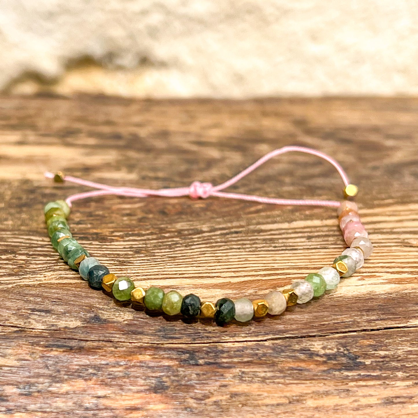 Bracelet ajustable composé de pierres fines naturelles de différentes teintes de Tourmaline ponctuées de perles d'hématites dorées.