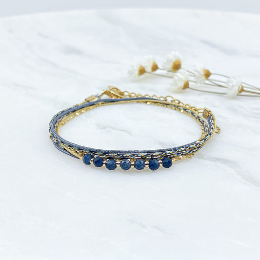 Bracelet composé de 4 liens en cordons doré et bleu et chaîne dorée. Sur l'un d'eux sont montées 7 perles rondes de pierre naturelles d'Agate bleue