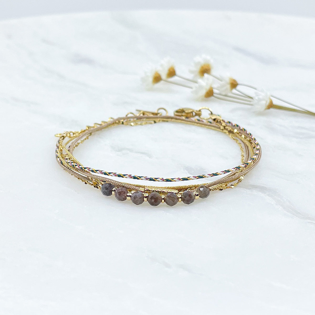 Bracelet composé de 4 liens en cordons doré et taupe et chaîne dorée. Sur l'un d'eux sont montées 7 perles rondes de pierre naturelles de Quartz Fumé brun taupe
