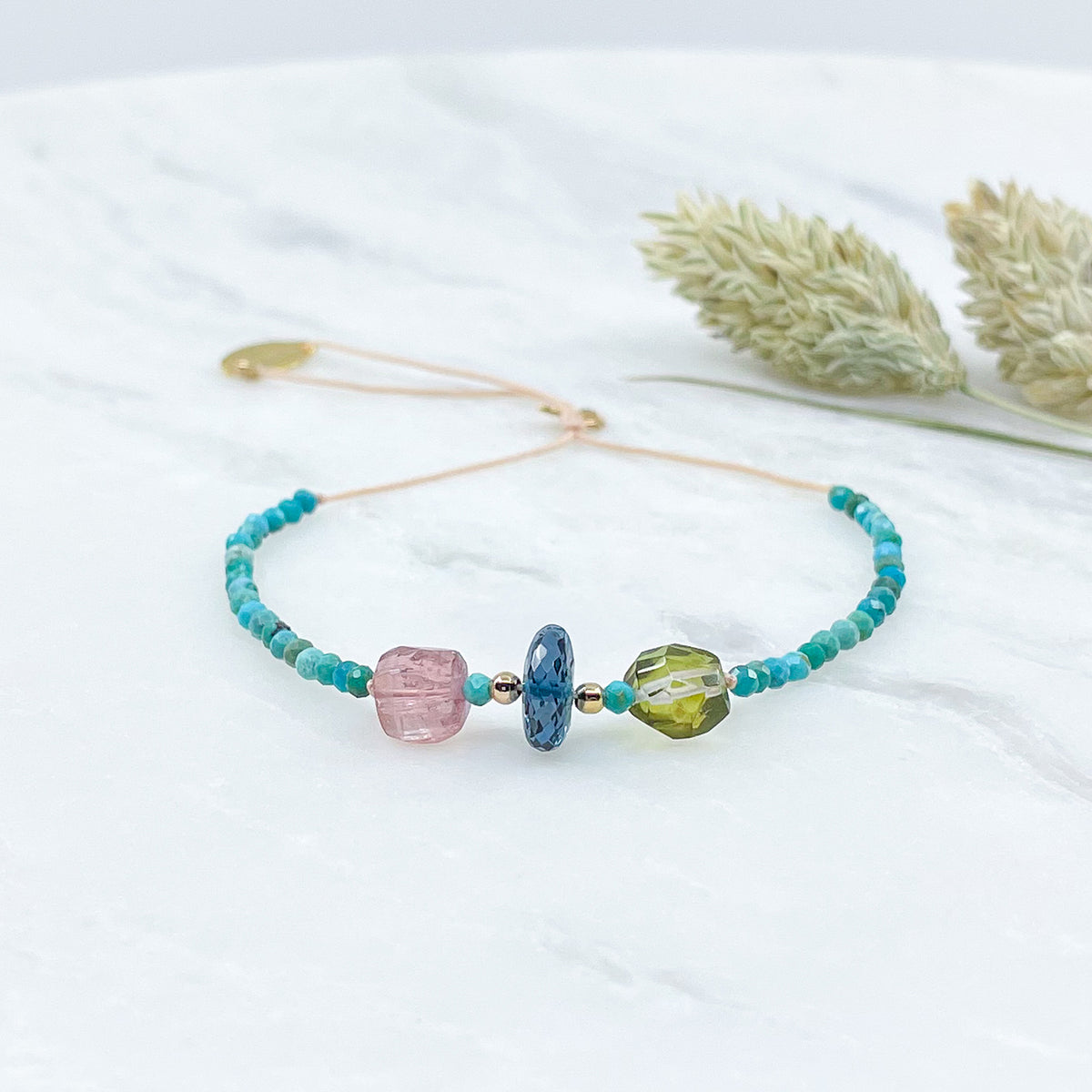 Bracelet aux teintes bleutées ajustable composé de pierres fines naturelles de Turquoise, de deux perles de Tourmaline facettées et d'une très belle perle de Topaze Bleu de Londres facettée