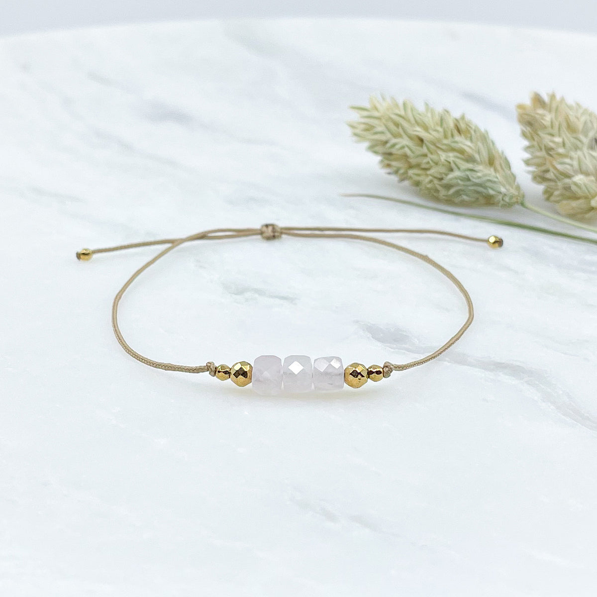 Bracelet réglable en pierres fines naturelles, 3 cubes facettés d'opale blanche légèrement rosée et perles d'hématites dorées.