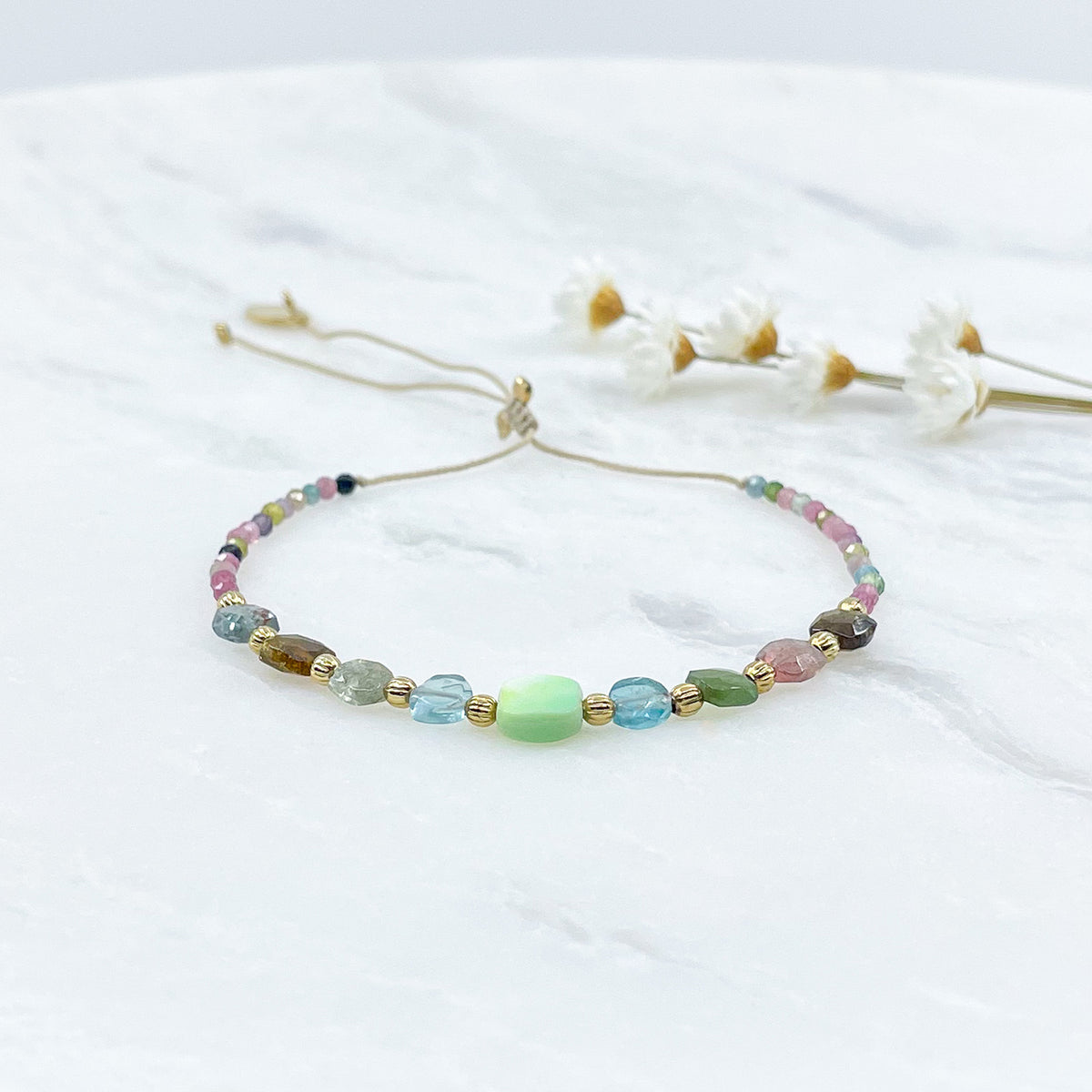 Bracelet ajustable en pierres fines naturelles. Au centre une Agathe d'Herbe carrée verte. Encadrée de six Tourmalines multicolores et deux Aigue-marine.
