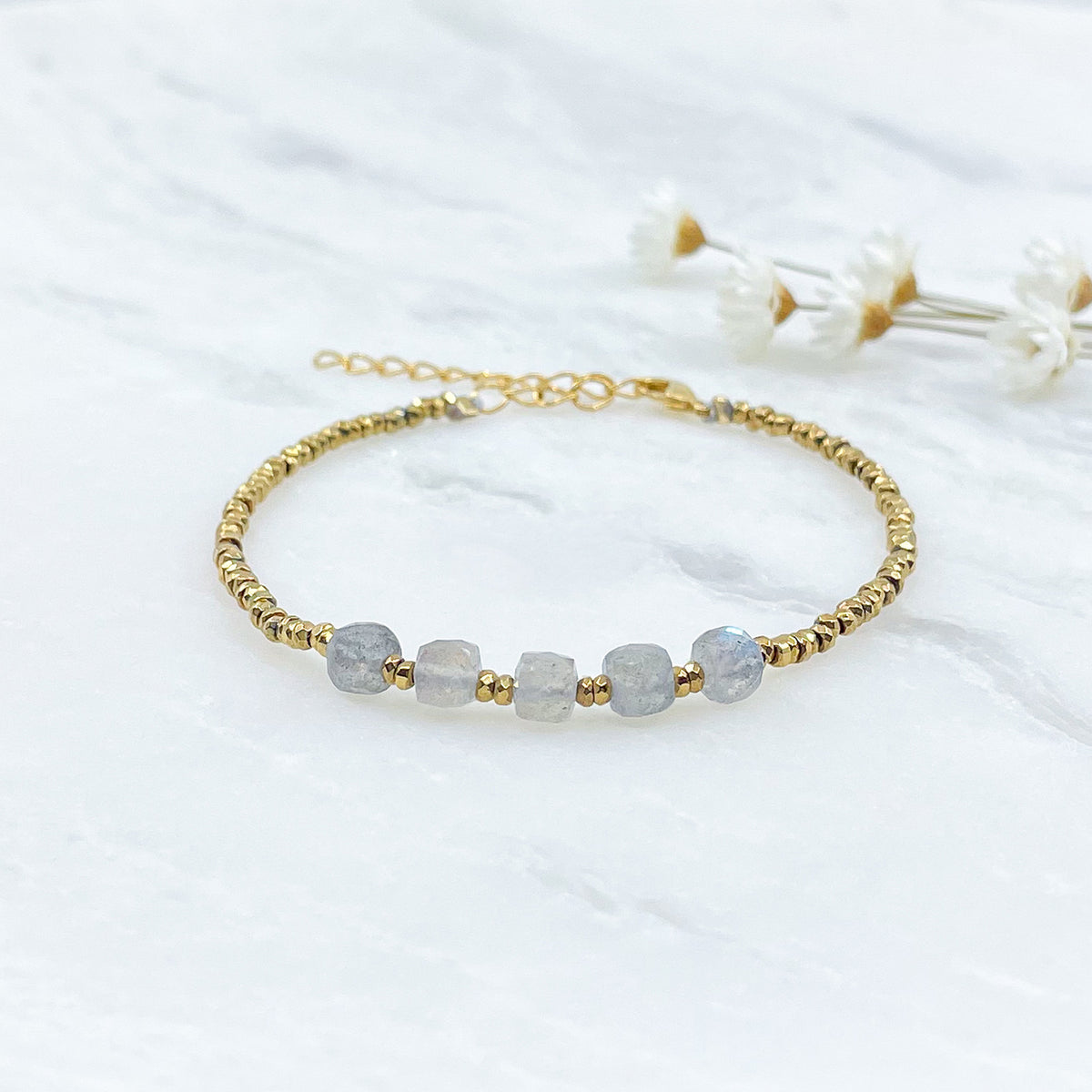 Bracelet en pierres fines naturelles de Labradorite. Cinq belles pierres cubiques facettées de labradorite montées en alternance avec des perles dorées. Ici avec un Jonc doré.
