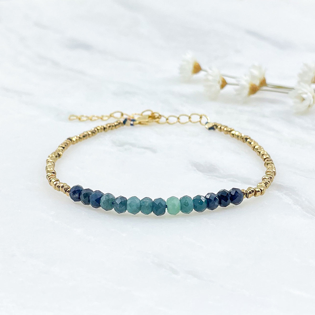 Bracelet en perles de pierres fines naturelles de Tourmaline bleu-vert intense. Elle sont encadrées de perles d'Hématites dorées.