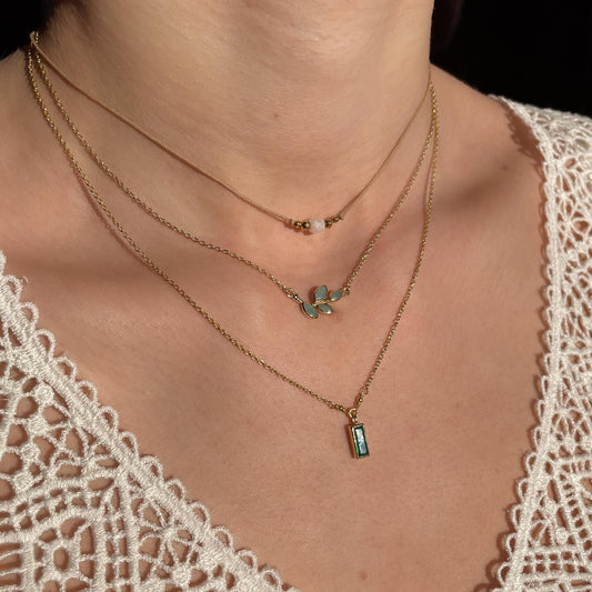 Collier cordon taille ajustable mettant en valeur une perle carrée facettée de pierre fine naturelle de Quartz Blanc entourée d'Hématite dorée.