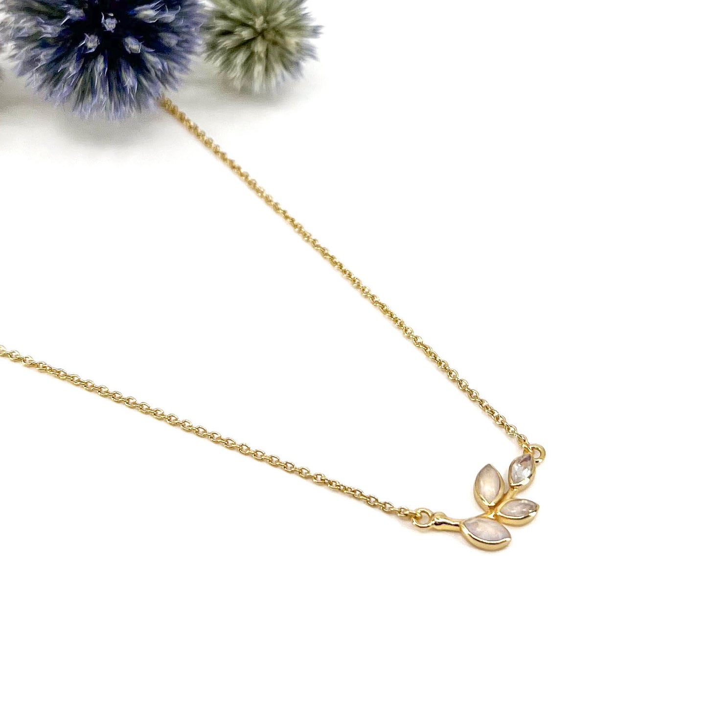 Collier plaqué or avec chaîne ajustable sur 3 niveaux de longueur différentes de 37 à 45 cm. Il met en valeur une brindille de feuillage réalisée en pierres fines naturelles de Pierre de Lune blanche au beaux reflets.