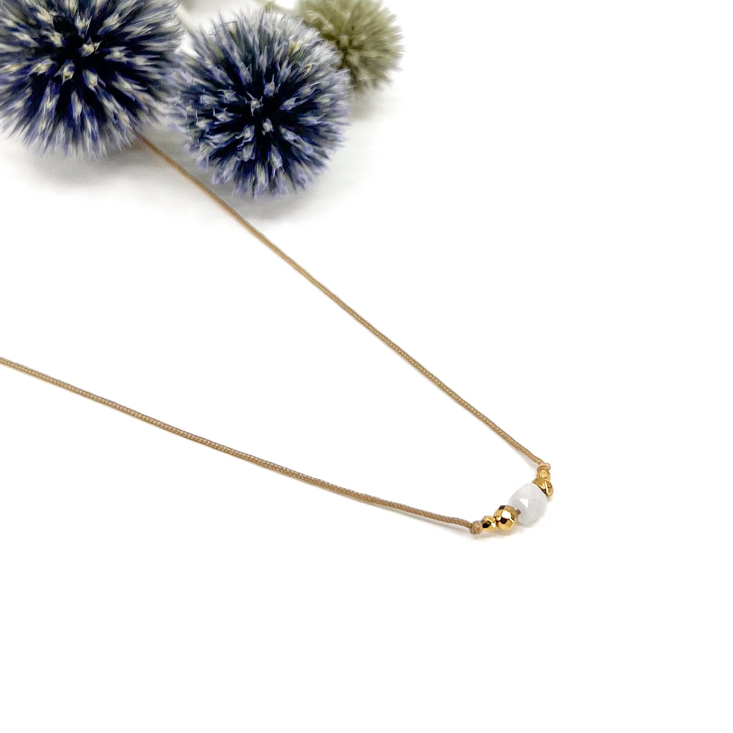 Collier cordon taille ajustable mettant en valeur une perle carrée facettée de pierre fine naturelle de Quartz Blanc entourée d'Hématite dorée.