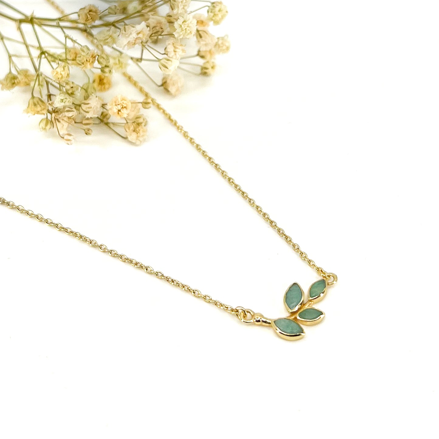Collier plaqué or avec chaîne ajustable sur 3 niveaux de longueur différentes de 37 à 45 cm. Il met en valeur une brindille de feuillage réalisée en pierres fines naturelles d'Amazonite vert lagon