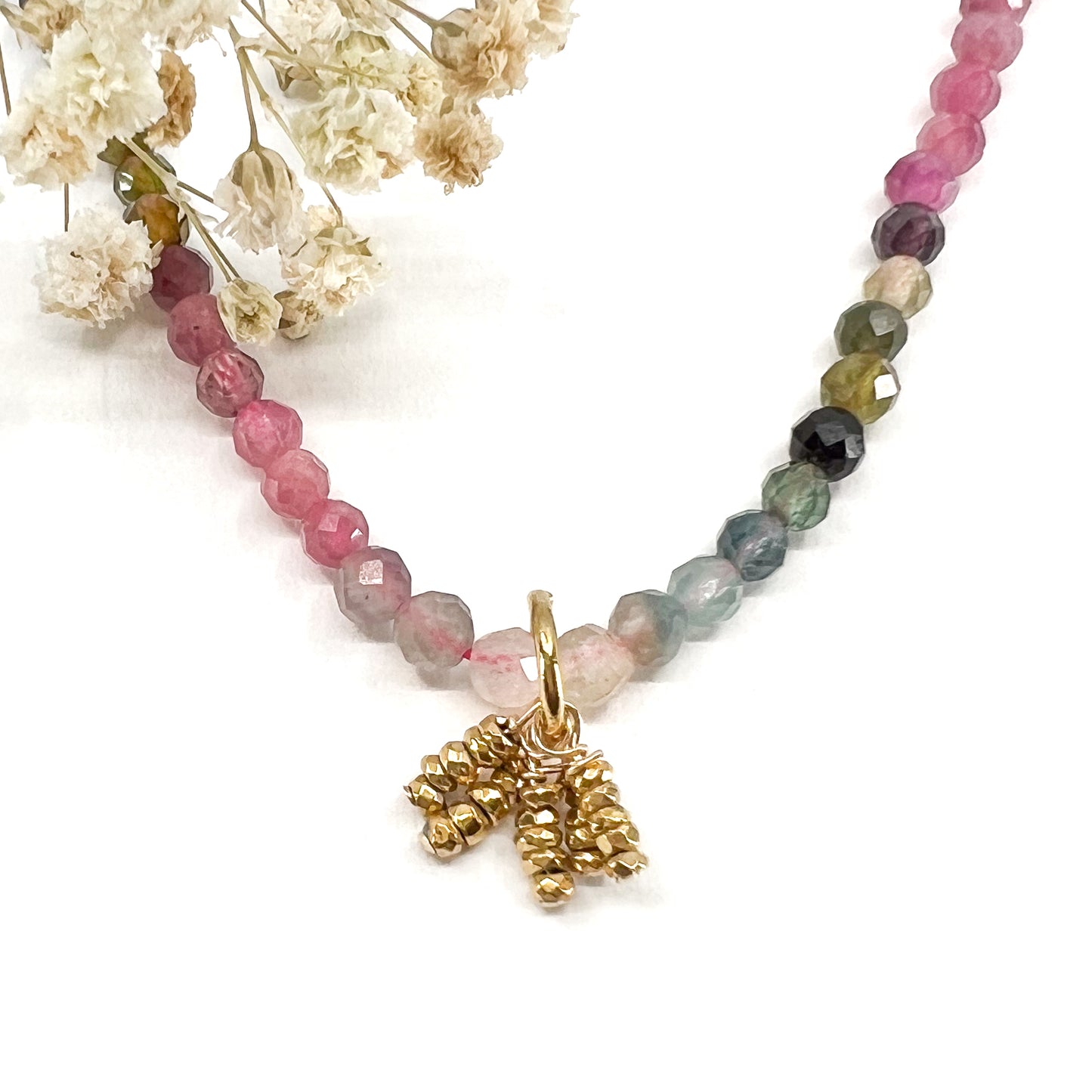 Collier rivière de perles de pierres fines naturelles de Tourmaline teinte arc-en-ciel. Pendentif composé de petites pierres d'hématite dorée. Chaîne de fermeture ajustable de 39 à 44 cm.