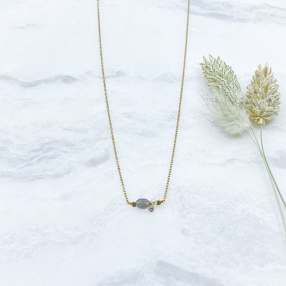Collier en pierre fine naturelle Labradorite orné d'une perle de culture et d'un petit pendentif cristal éclatant. Monté sur chaîne dorée en acier inoxydable.
