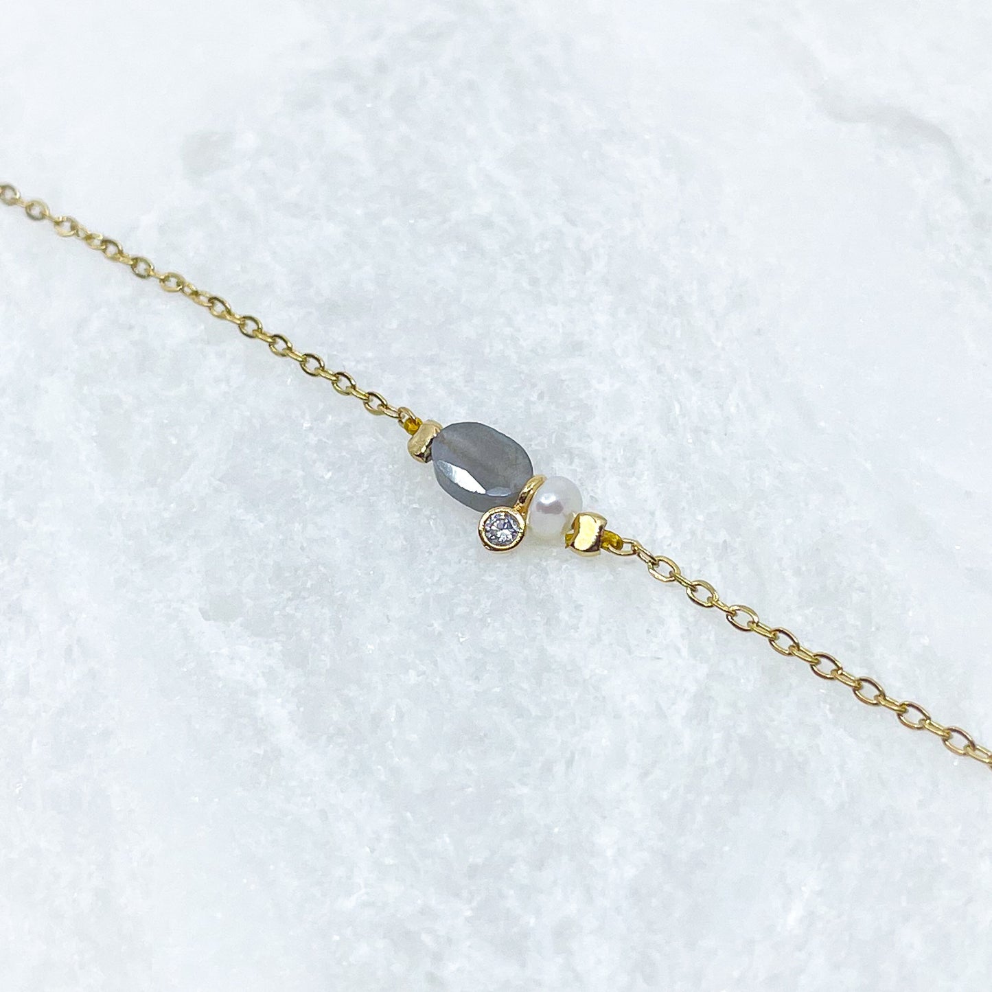 Collier en pierre fine naturelle Labradorite orné d'une perle de culture et d'un petit pendentif cristal éclatant. Monté sur chaîne dorée en acier inoxydable.