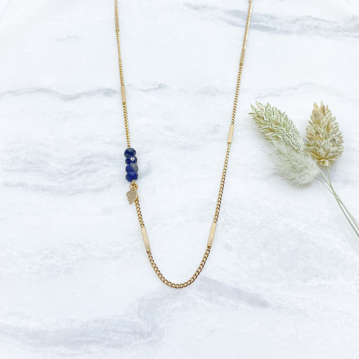 Collier sautoir long 85cm chaîne plaqué or recyclé. 4 pierres fines naturelles de sodalite d'un bleu profond ponctuent le côté du sautoir. Alternance de mailles longues rectangulaires sur une chaîne classique