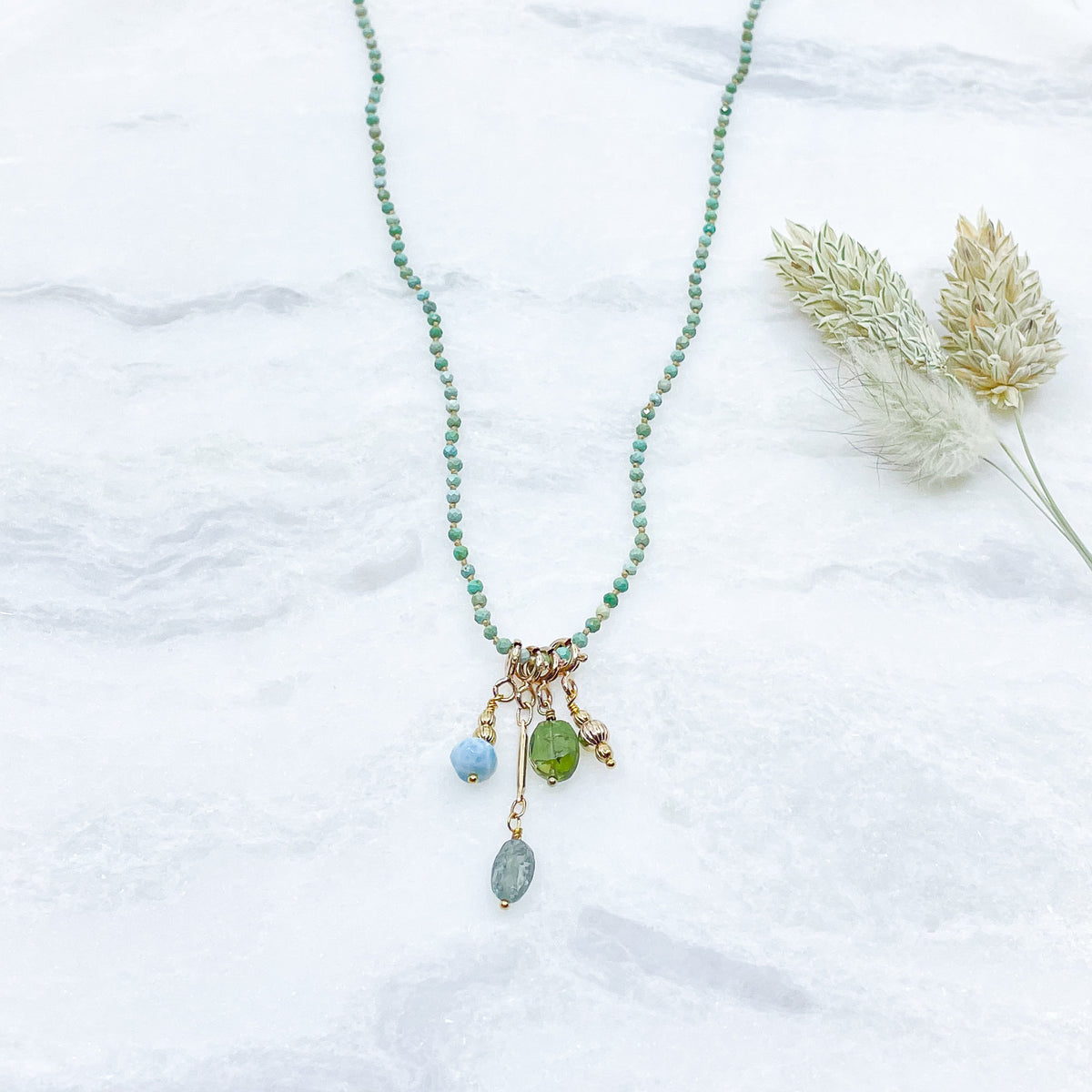 Collier 36 cm en Turquoise aux tons verts et 4 charms composés de différentes pierres fines naturelles et d'un pendentif plaqué or