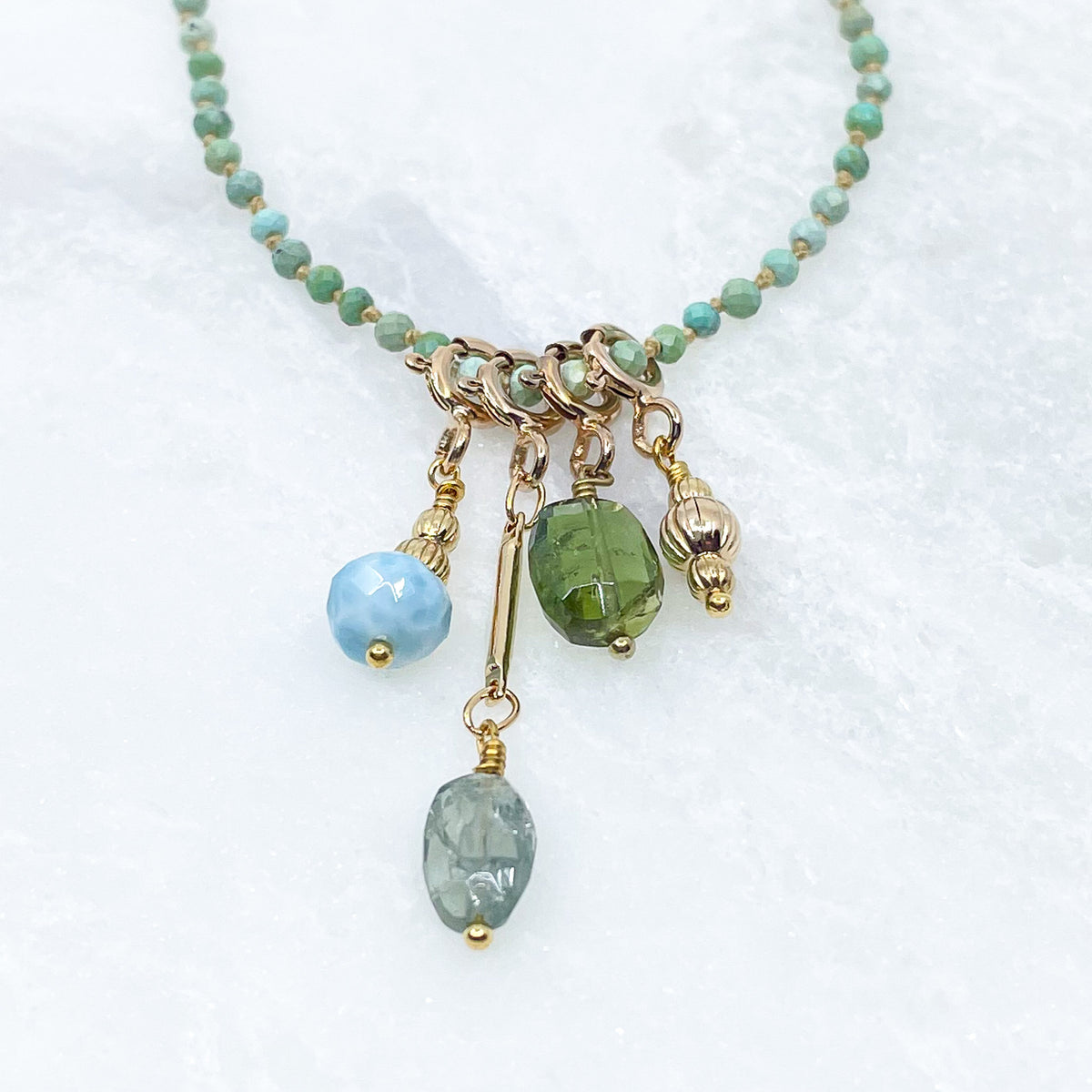 Collier 36 cm en Turquoise aux tons verts et 4 charms composés de différentes pierres fines naturelles et d'un pendentif plaqué or