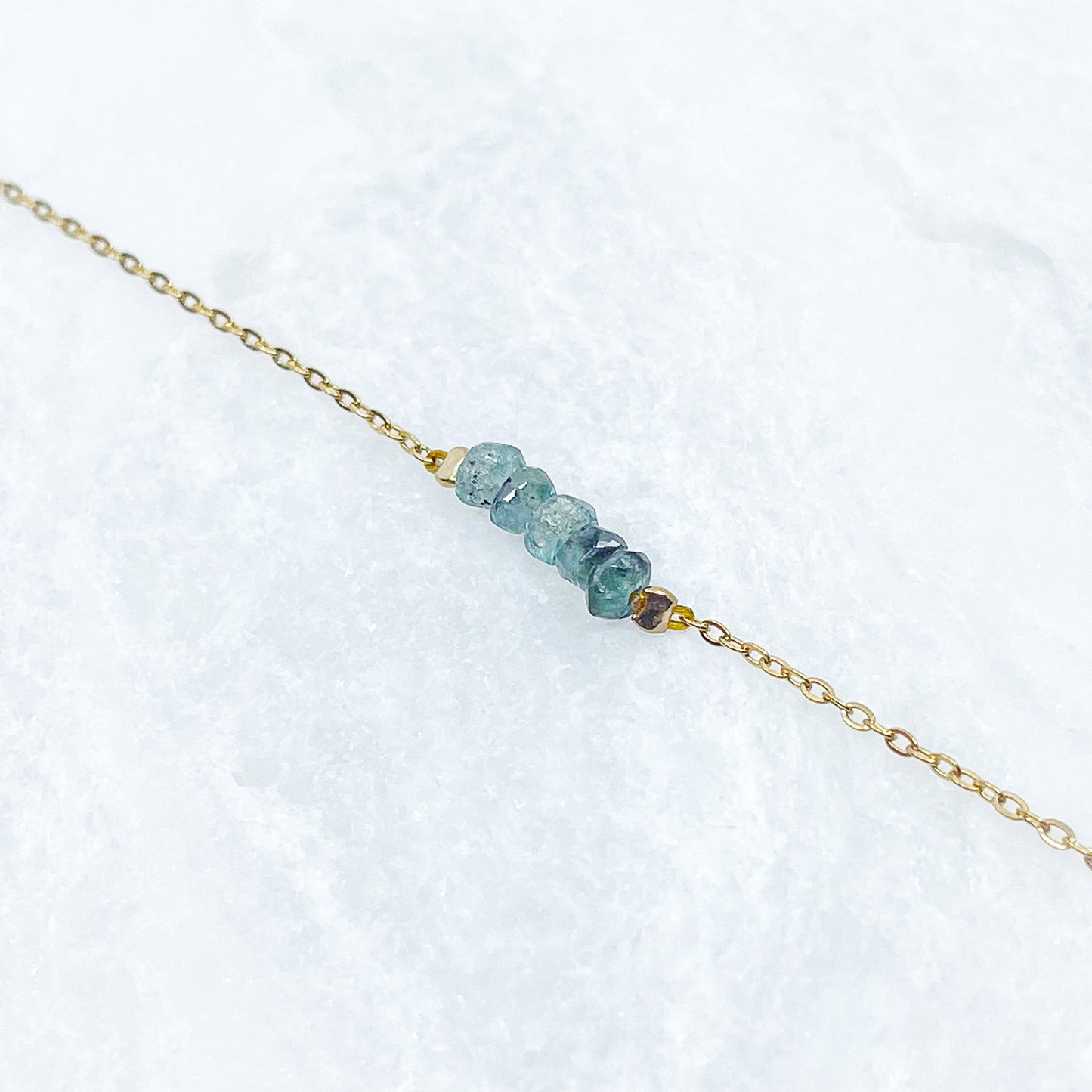 Collier en pierres fines naturelles de Tourmaline aux déclinaison bleu-vert. 5 pierres montées sur une chaîne en acier inoxydable doré.