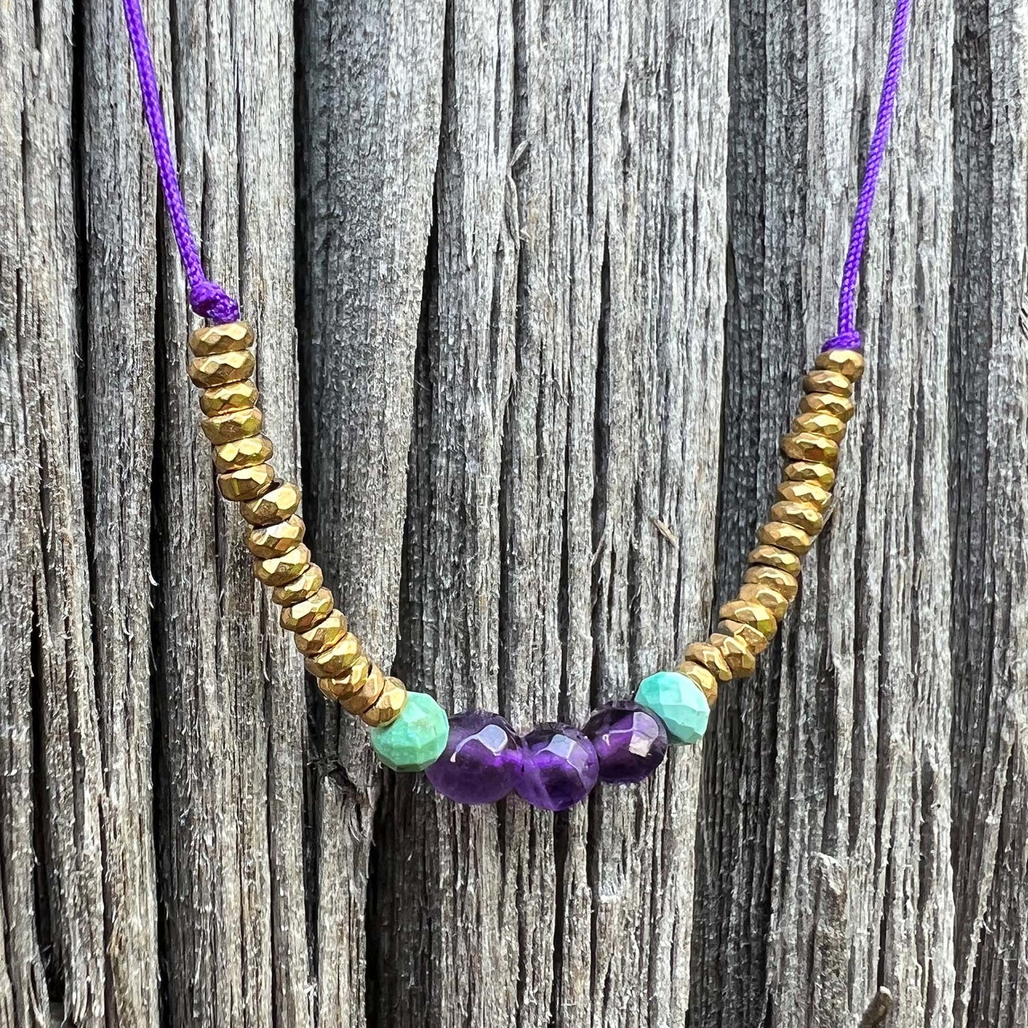Collier sur cordon ajustable. Pierres fines naturelles : 3 perles d'améthyste encradrées par deux perles de Turquoise et des hématites dorées.
