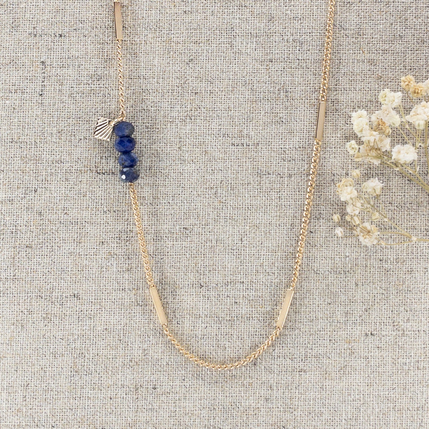 Collier sautoir long 85cm chaîne plaqué or recyclé. 4 pierres fines naturelles de sodalite d'un bleu profond ponctuent le côté du sautoir. Alternance de mailles longues rectangulaires sur une chaîne classique