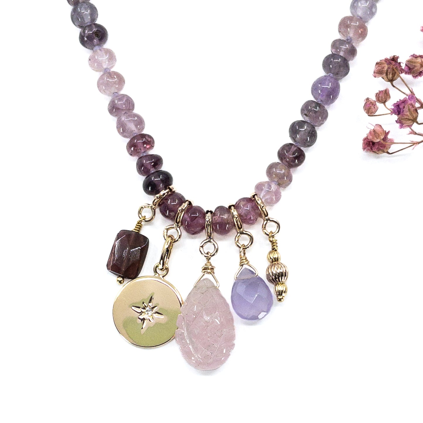 Collier long de 58 cm en pierres fines naturelles de spinelle dans des dégradés de rose à bleu gris. 5 charms : 3 pierres fines naturelles de teintes harmonieuses, une médaille ronde et un pendentif en petites perles plaqué or. Chaîne de réglage de 4 cm et fermoir plaqué or 18 carats