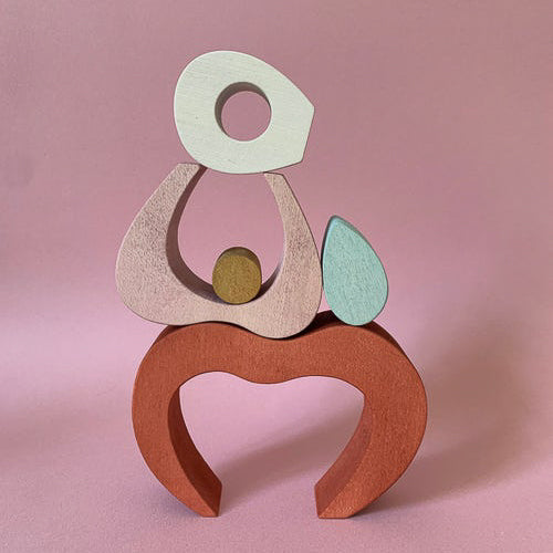 Jeu en bois en forme de pomme composé de différents éléments empilables. Teinte rouge rosée. A partir de 3 ans.