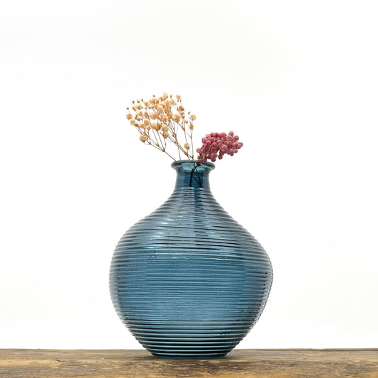 Vase en verre bleu cyclade. Hauteur 20 cm, diamètre 16.5 cm. Design épuré, stries le long du vase. Livré avec fleurs séchées offertes.