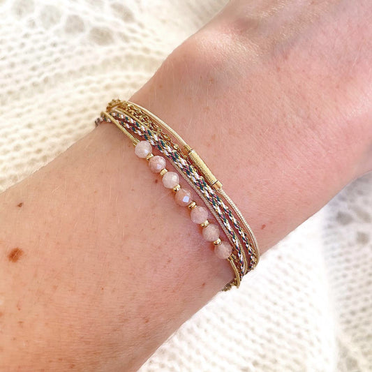 Bracelet composé de 4 liens en cordons dorés et chaîne dorée. Sur l'un d'eux sont montées 7 perles rondes de pierre naturelles de pierre de lune pêche.