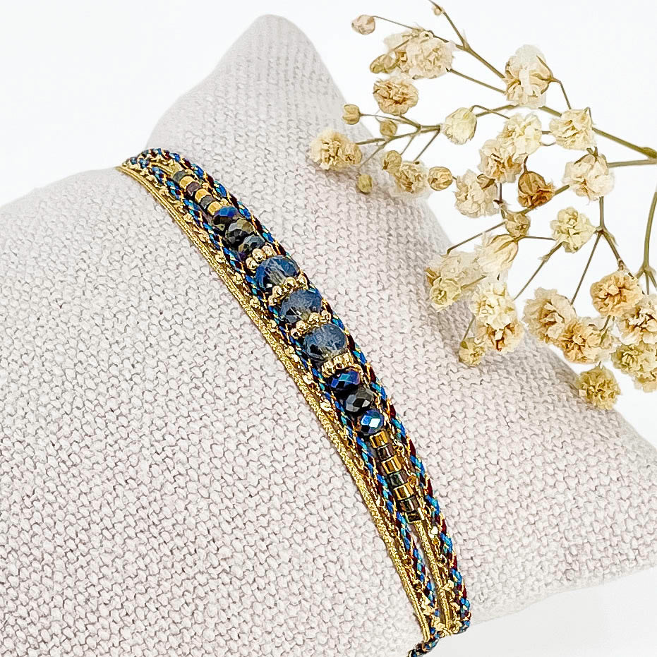 Bracelet composé de 3 liens en cordons colorés et doré et chaîne dorée. Sur l'un d'eux sont montées des perles de verre de Cristal bleu aux beaux reflets.