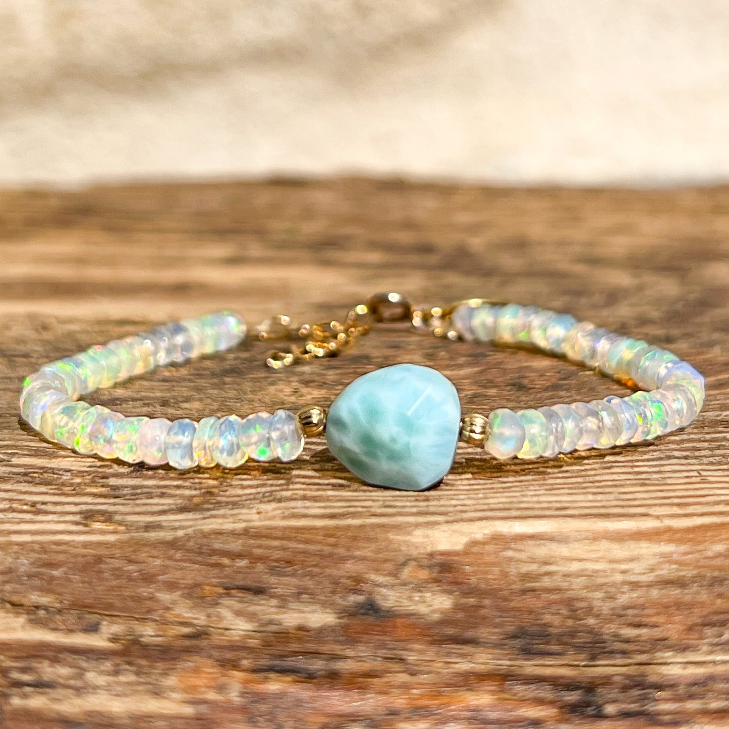 Bracelet en pierres fines naturelles composé d'une pierre facettée de Larimar en forme de galet bleu clair, entouré d'une longue rivière d'Opales aux mille reflets iridescents