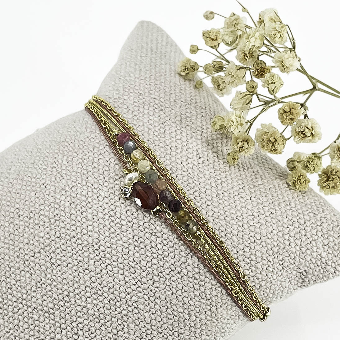Bracelet composé de 3 liens cordons et chaîne s'enroulant en deux tours sur le poignet. Il met en valeur les perles de pierre naturelle de Tourmaline ainsi qu'un Grenat, une Perle de Culture et un petit pendentif serti d'un cristal. Pierres et perles sont montées sur les différents liens.