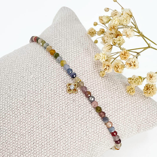 Bracelet pierres naturelles perles de tourmaline multicolores. En son centre un petit pendentif trèfle doré serti d'un cristal.
