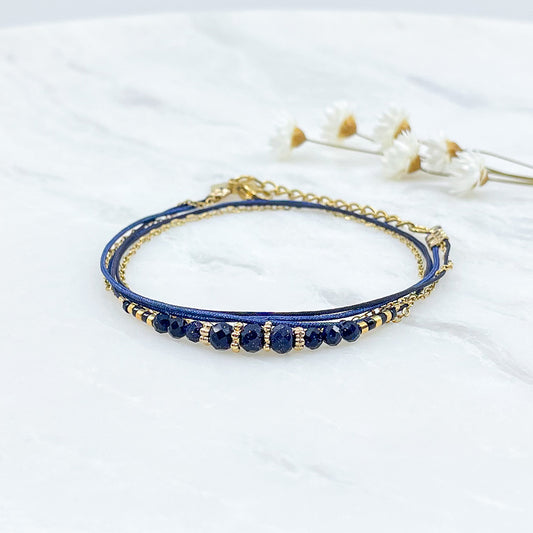 Bracelet en perles de cristal de verre bleu nuit. Trois liens de cordons et chaîne qui s'enroulent en deux tours sur le poignet. Jonc doré à l'or fin. 