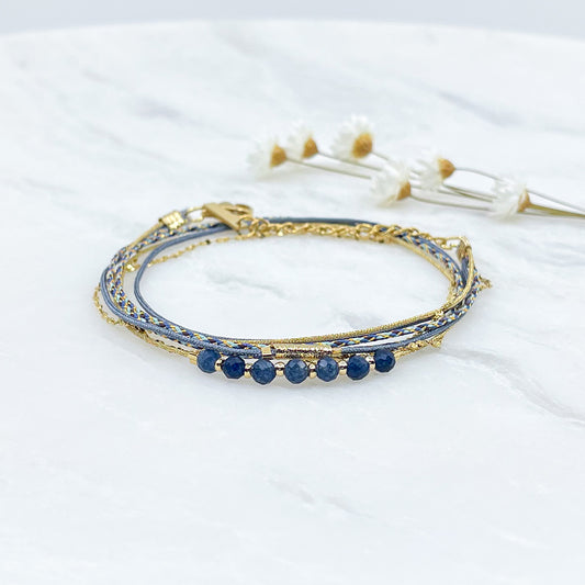 Bracelet composé de 4 liens en cordons doré et bleu et chaîne dorée. Sur l'un d'eux sont montées 7 perles rondes de pierre naturelles d'Agate bleue