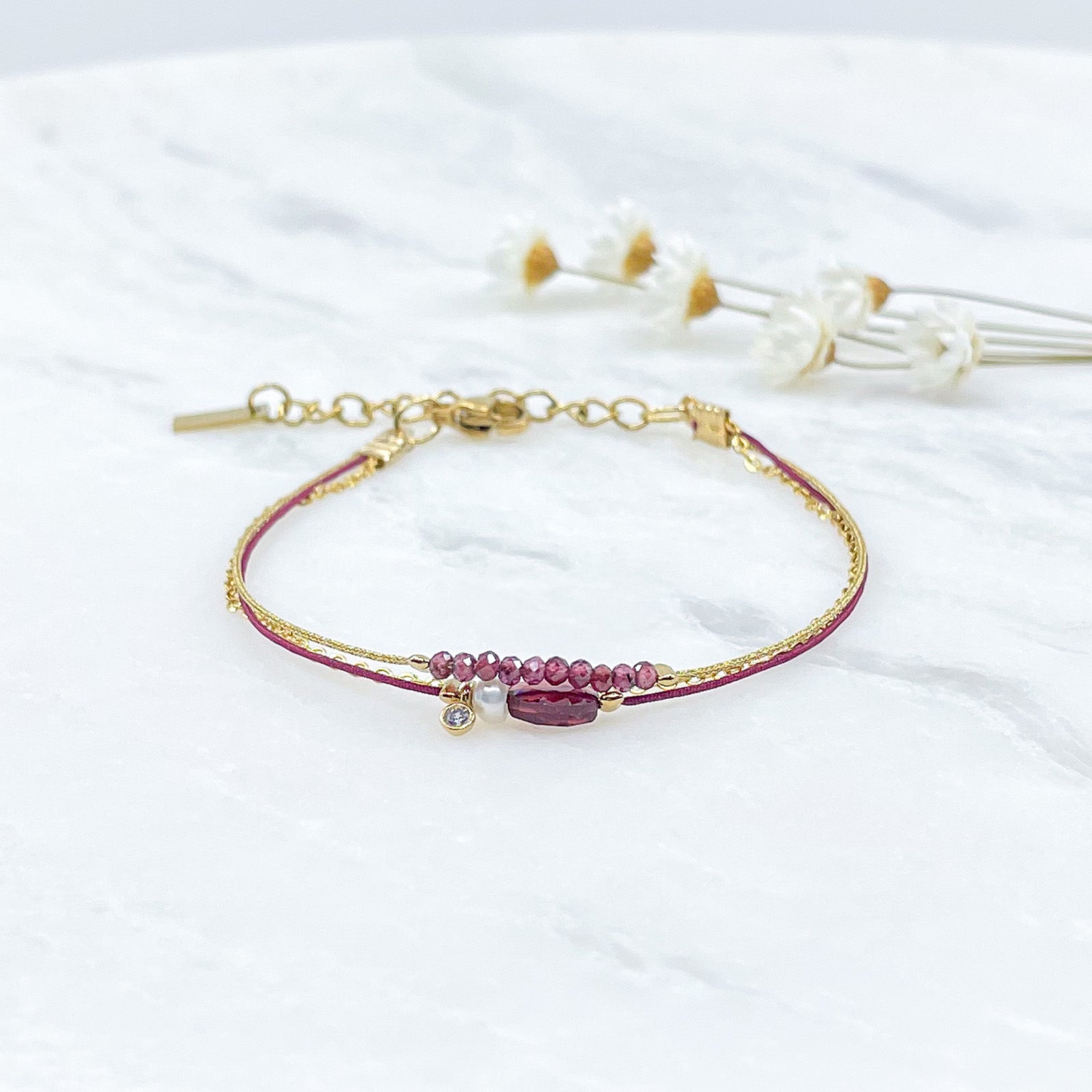 Bracelet Grenat et Perle de Culture montés sur différents liens cordons et chaîne dorée.