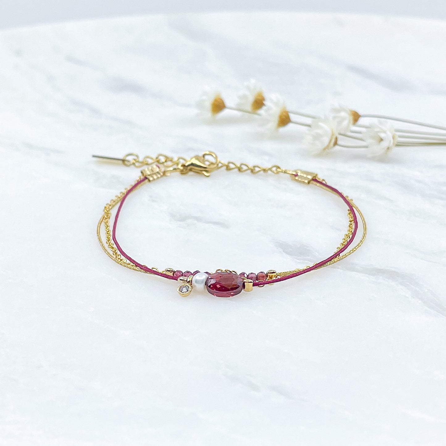 Bracelet Grenat et Perle de Culture montés sur différents liens cordons et chaîne dorée.