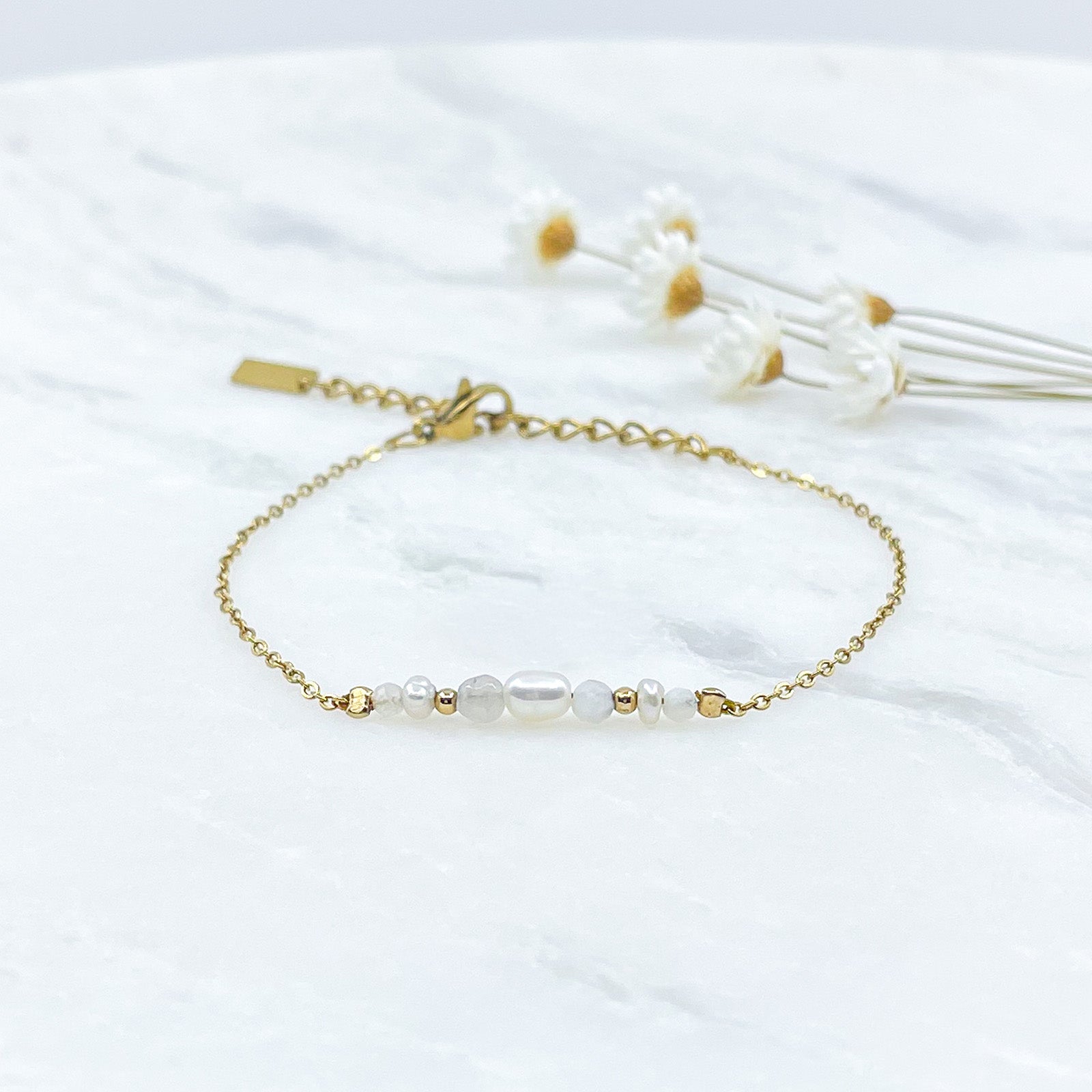 Bracelet monté avec une alternance de perles de culture et de pierres de lune naturelles et perle de verre pailletée de teinte terracotta sur une chaîne dorée.