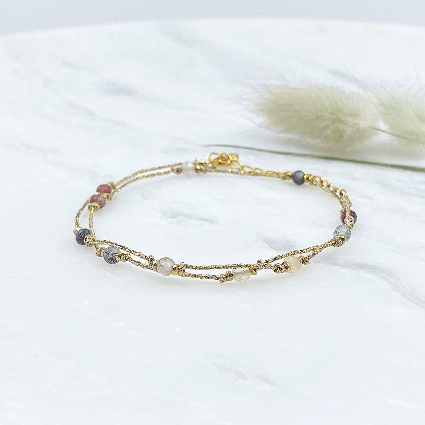 Bracelet perles de pierres fines naturelles variées au coloris assortis. S'enroule en deux tours autour du poignet. Montées sur cordon avec fermoir et chaîne de rallonge.